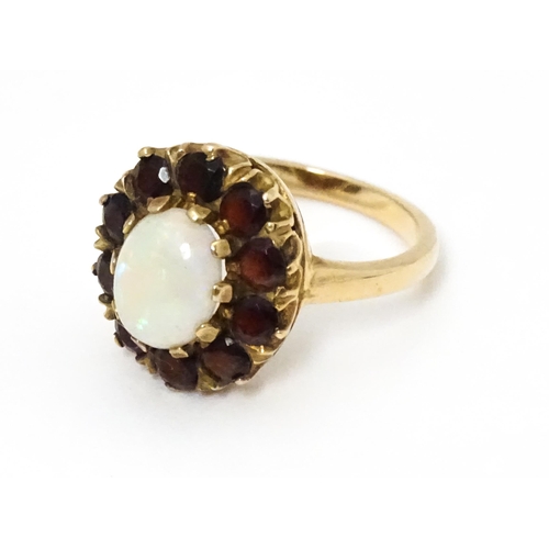 658 - A 9ct gold ring set with central opal bordered by garnets. Ring size approx. L