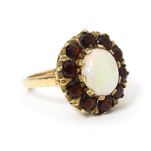 658 - A 9ct gold ring set with central opal bordered by garnets. Ring size approx. L