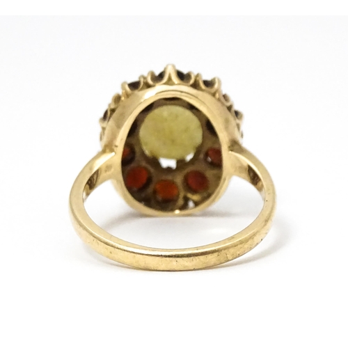 658 - A 9ct gold ring set with central opal bordered by garnets. Ring size approx. L