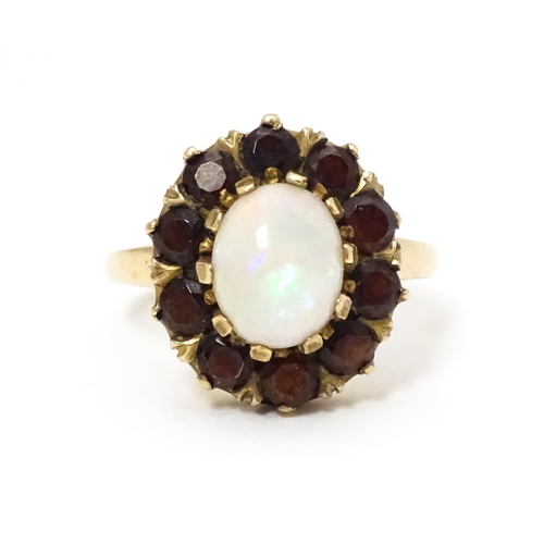 658 - A 9ct gold ring set with central opal bordered by garnets. Ring size approx. L