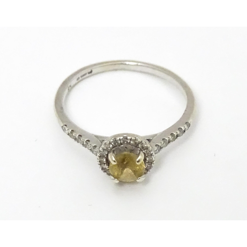 660 - A 9ct white gold ring set with central citrine coloured stone bordered by diamonds and with further ... 