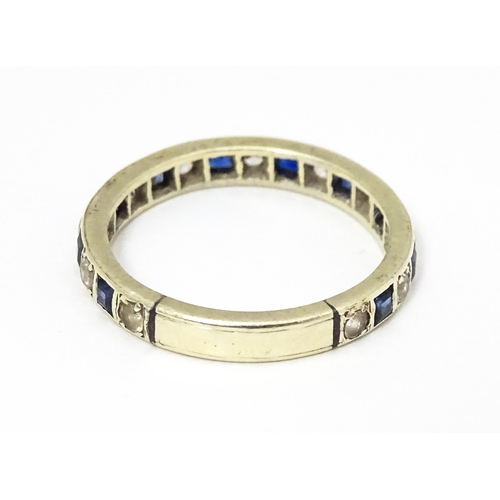 666 - A white metal eternity ring set with blue and white stones. Ring size approx p 1/2