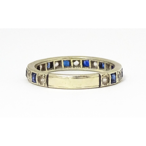 666 - A white metal eternity ring set with blue and white stones. Ring size approx p 1/2