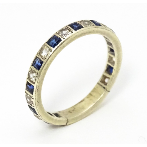 666 - A white metal eternity ring set with blue and white stones. Ring size approx p 1/2