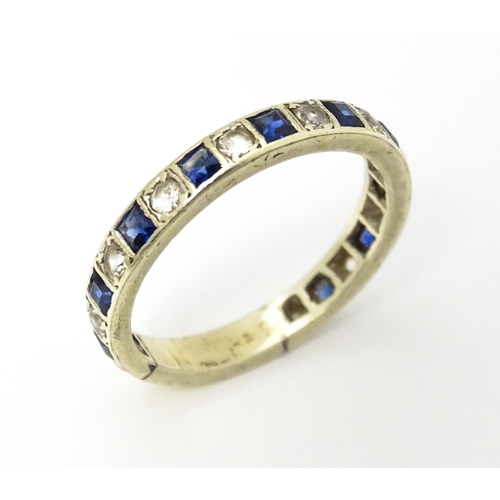 666 - A white metal eternity ring set with blue and white stones. Ring size approx p 1/2