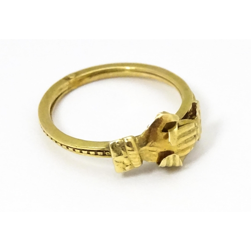 668 - A yellow metal gimmal / gimmel ring the three bands uniting as one, with a pair of interlocking hand... 