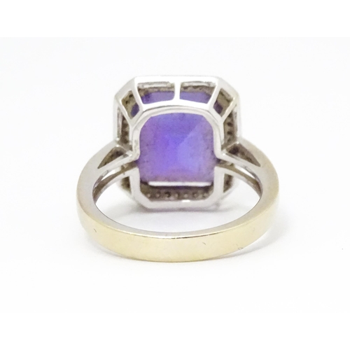 679 - An 18ct gold ring set with central amethyst bordered by diamonds with further diamonds to shoulders.... 