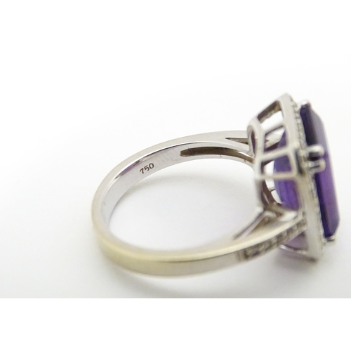 679 - An 18ct gold ring set with central amethyst bordered by diamonds with further diamonds to shoulders.... 