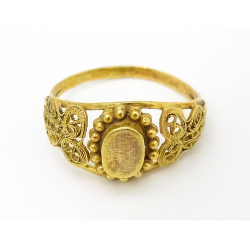 680 - A yellow metal ring with filigree decoration. Ring size approx. K 1/2