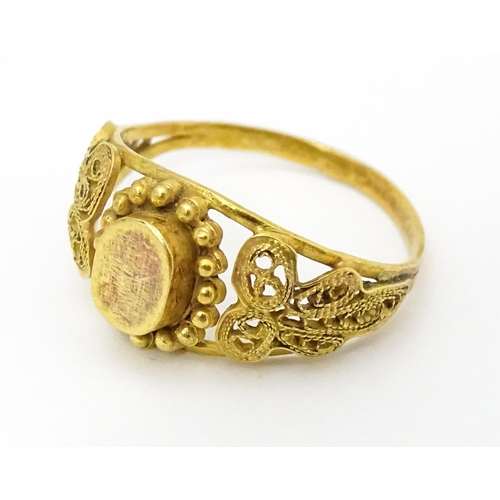 680 - A yellow metal ring with filigree decoration. Ring size approx. K 1/2