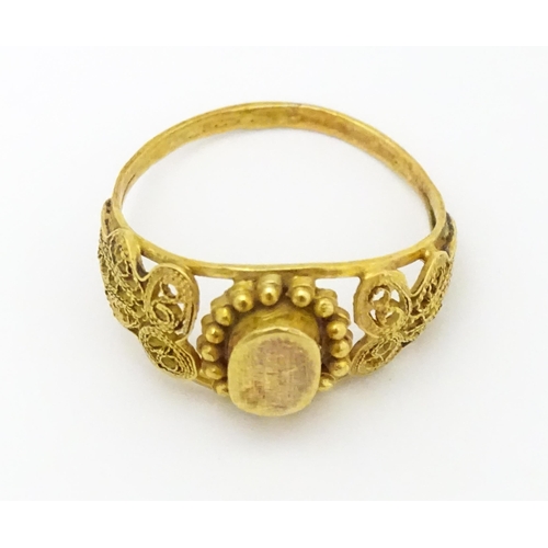 680 - A yellow metal ring with filigree decoration. Ring size approx. K 1/2