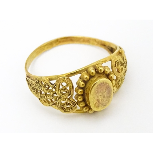 680 - A yellow metal ring with filigree decoration. Ring size approx. K 1/2