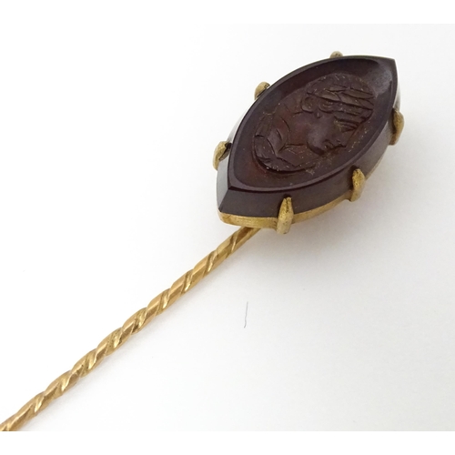 707 - A yellow metal stick pin with carved intaglio to top. Approx 2 3/4