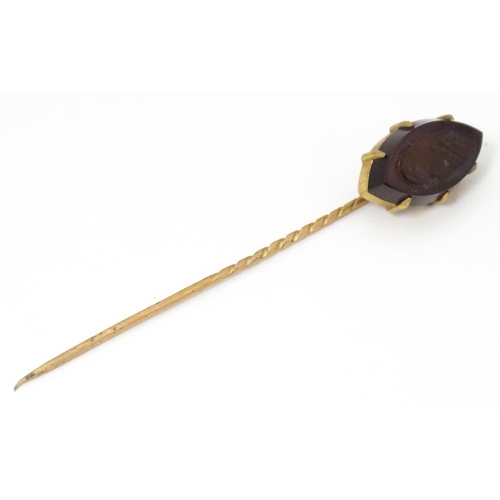 707 - A yellow metal stick pin with carved intaglio to top. Approx 2 3/4