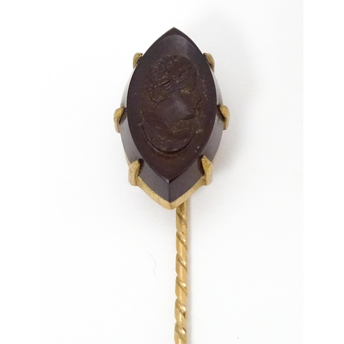 707 - A yellow metal stick pin with carved intaglio to top. Approx 2 3/4