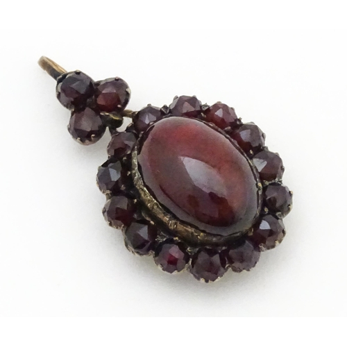 710 - A pendant locket with central garnet cabochon bordered by further garnets. Approx 1 1/4