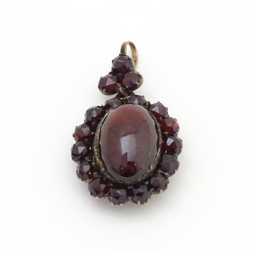 710 - A pendant locket with central garnet cabochon bordered by further garnets. Approx 1 1/4