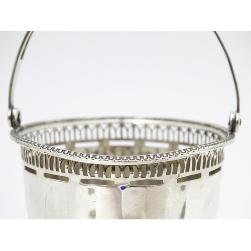 401 - A silver pedestal sugar basket with swing handle and blue glass liner, hallmarked Birmingham 1925 ma... 