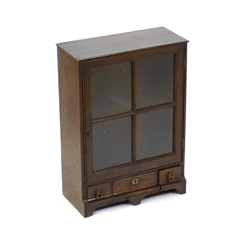 1442 - A late Georgian table top cabinet with an astragal glazed door above three short drawers raised on s... 