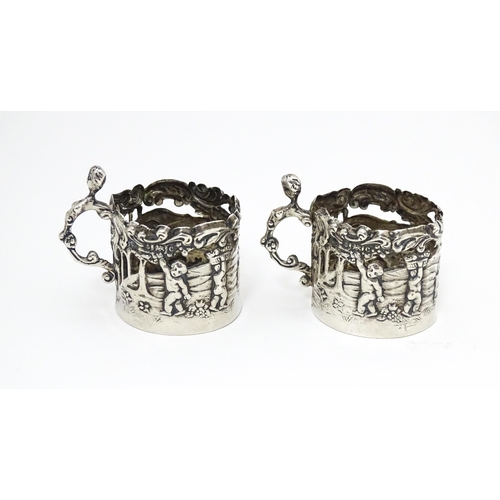 460 - A pair of miniature silver cup sleeves / tot glass holders with embossed and pierced decoration, hal... 