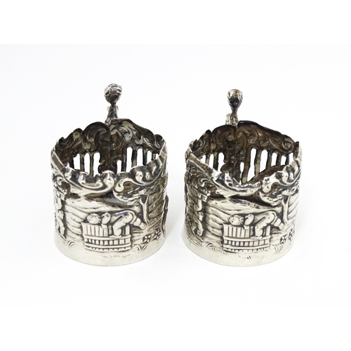 460 - A pair of miniature silver cup sleeves / tot glass holders with embossed and pierced decoration, hal... 