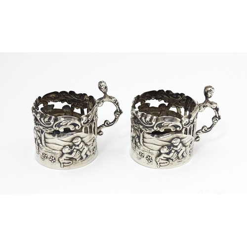 460 - A pair of miniature silver cup sleeves / tot glass holders with embossed and pierced decoration, hal... 