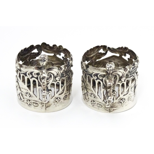 460 - A pair of miniature silver cup sleeves / tot glass holders with embossed and pierced decoration, hal... 