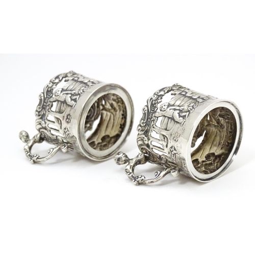 460 - A pair of miniature silver cup sleeves / tot glass holders with embossed and pierced decoration, hal... 