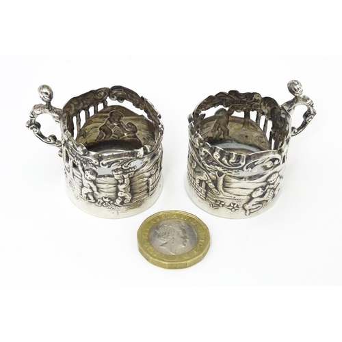 460 - A pair of miniature silver cup sleeves / tot glass holders with embossed and pierced decoration, hal... 