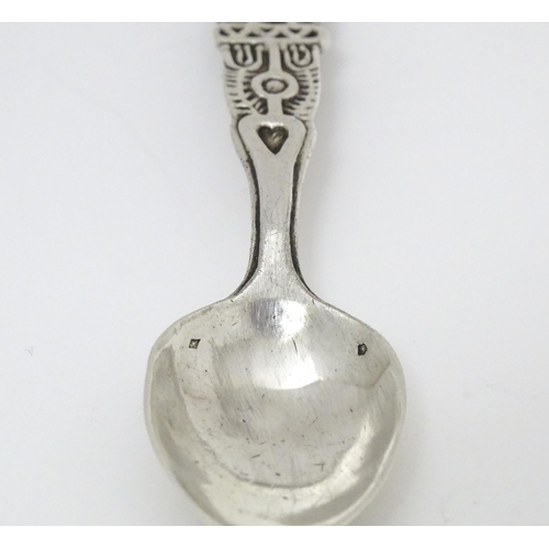 502 - A white metal Arts & Crafts teaspoon with hammered bowl and scroll detail to handle. Together with a... 