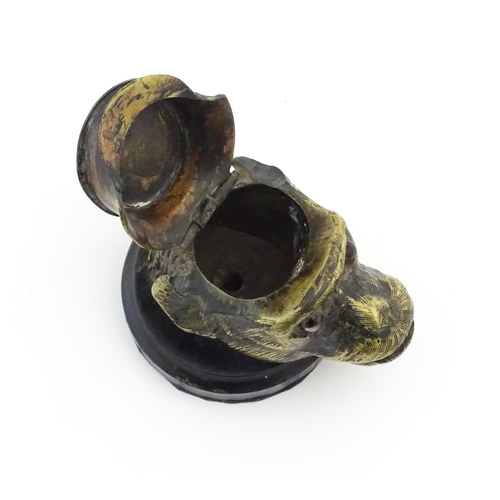 1192 - A Victorian novelty brass desk inkwell formed as the head of a monkey with glass eyes wearing a hat.... 