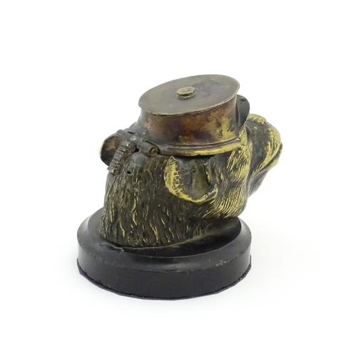 1192 - A Victorian novelty brass desk inkwell formed as the head of a monkey with glass eyes wearing a hat.... 