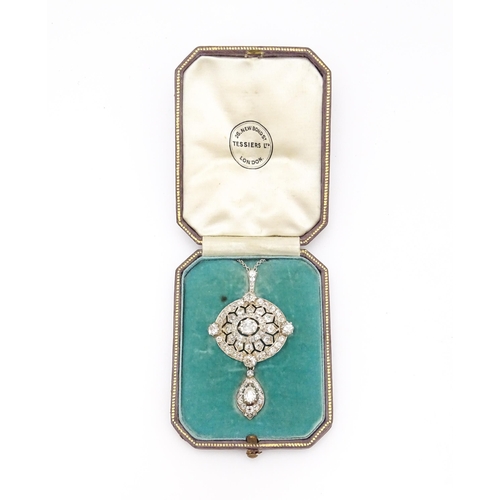 An impressive early 20thC diamond pendant / brooch of oval form set with a profusion of diamonds with further diamonds set to the central lower drop. With brooch and pendant fitting. In original fitted case marked Tessiers Ltd 26 New Bond St London. The pendant 2 1/4" long x 1 1/4" wide with a chain 16" long