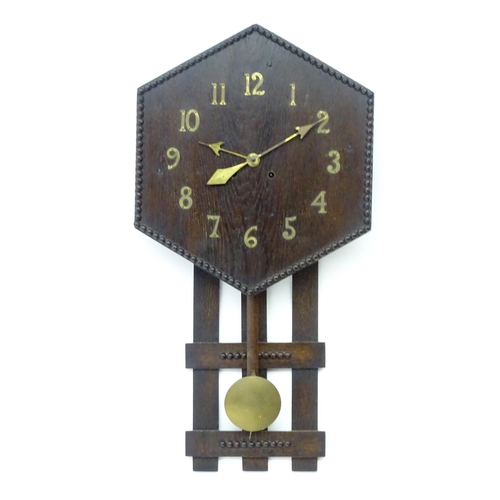 An Arts and Crafts style oak wall clock, the hexagonal dial with Arabic brass numerals and stylised hands. Approx  32" high x 16 1/4" wide Inspired by Gustave Stickley / mission oak.