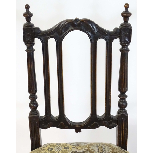 78 - A pair of late 19thC carved oak side chairs surmounted by turned finials and having carved cresting ... 