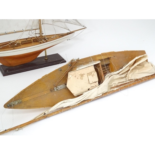 90 - A mid 20thC wooden pond yacht / model boat on stand, with painted finish and cotton sails, together ... 