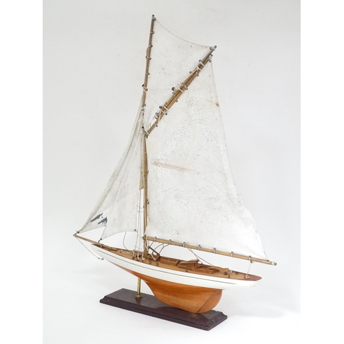 90 - A mid 20thC wooden pond yacht / model boat on stand, with painted finish and cotton sails, together ... 