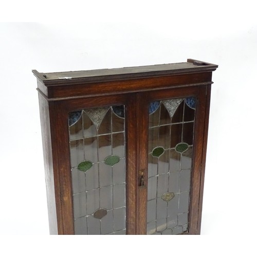 102 - An early 20thC oak cabinet with two leaded glass panelled doors. Approx 34