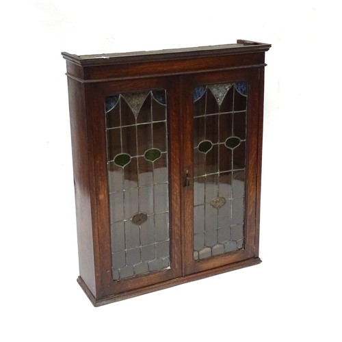 102 - An early 20thC oak cabinet with two leaded glass panelled doors. Approx 34