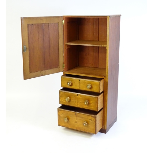 107 - A late 19thC / early 20thC mahogany cabinet with a panelled door above three short drawers with turn... 