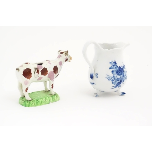 137 - A Swansea cow creamer. Together with a Continental blue and white three footed jug decorated with fl... 