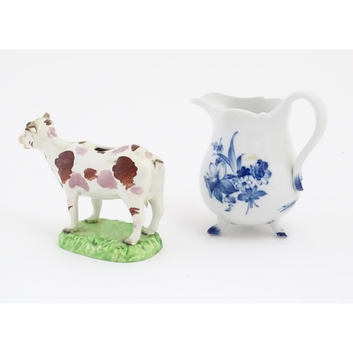 137 - A Swansea cow creamer. Together with a Continental blue and white three footed jug decorated with fl... 