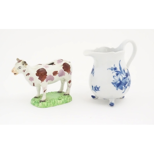 137 - A Swansea cow creamer. Together with a Continental blue and white three footed jug decorated with fl... 