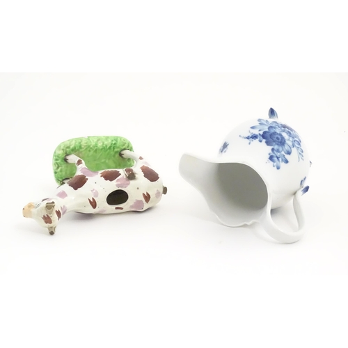 137 - A Swansea cow creamer. Together with a Continental blue and white three footed jug decorated with fl... 