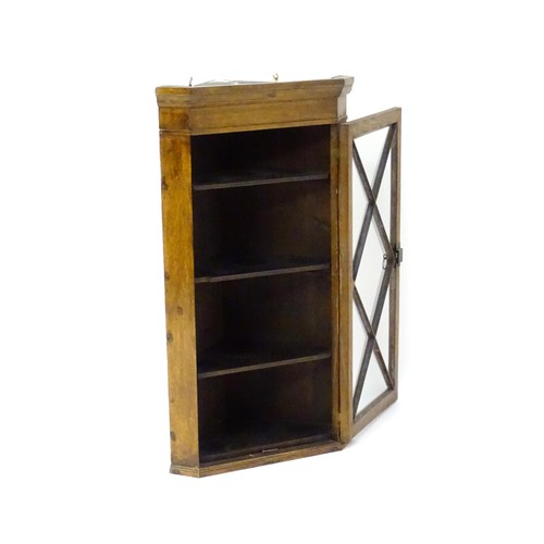 172 - An early 20thC oak corner cupboard with a moulded cornice above an astragal glazed door containing f... 