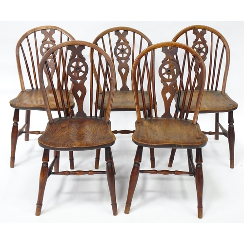 98 - A set of five late 19thC / early 20thC wheelback dining chairs with shaped elm seats and raised on t... 