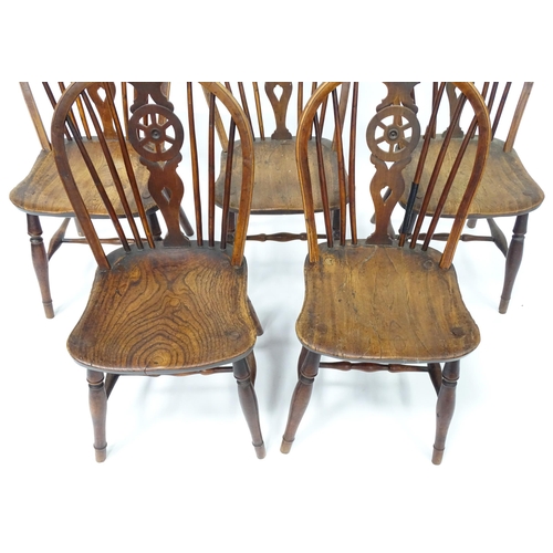 98 - A set of five late 19thC / early 20thC wheelback dining chairs with shaped elm seats and raised on t... 