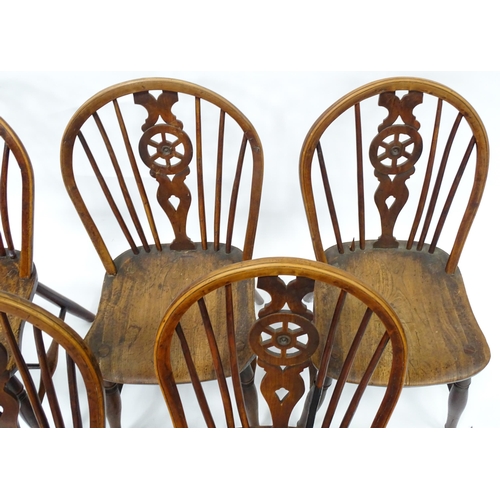 98 - A set of five late 19thC / early 20thC wheelback dining chairs with shaped elm seats and raised on t... 
