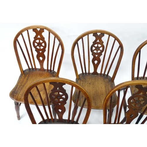 98 - A set of five late 19thC / early 20thC wheelback dining chairs with shaped elm seats and raised on t... 