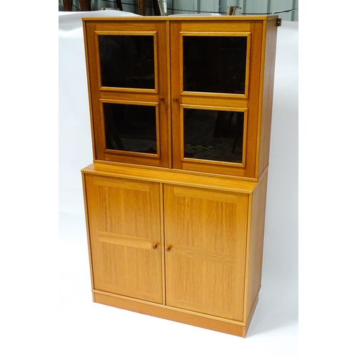 834 - Two c1970s teak cupboards, each consisting of a glazed (tinted) shelving unit above a floor standing... 